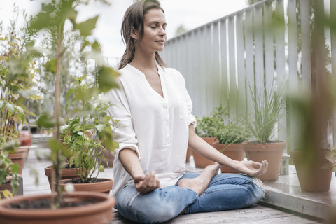 Frau sitzt auf Balkon und übt Yoga, lizenzfreies Stockfoto