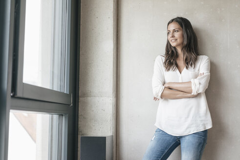 Lächelnde Frau schaut aus dem Fenster - JOSF01649