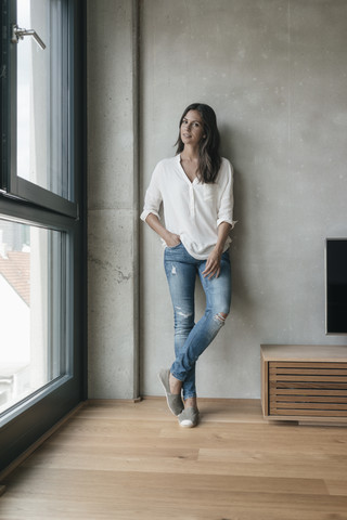 Frau an Betonwand stehend, lizenzfreies Stockfoto