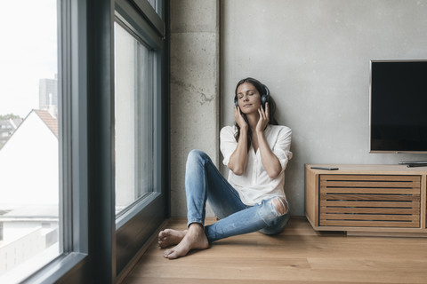 Entspannte Frau beim Musikhören zu Hause, lizenzfreies Stockfoto