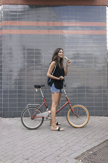 Smiling woman with ice lolly and bicycle - JOSF01667