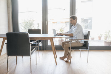 Young man using laptop at table - JOSF01669