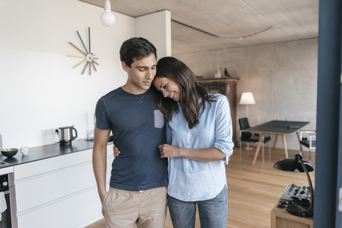 Happy couple hugging in kitchen at home stock photo