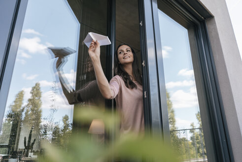 Woman holding paper plane at the window - JOSF01686