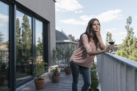 Woman with glass of red wine relaxing on balcony stock photo