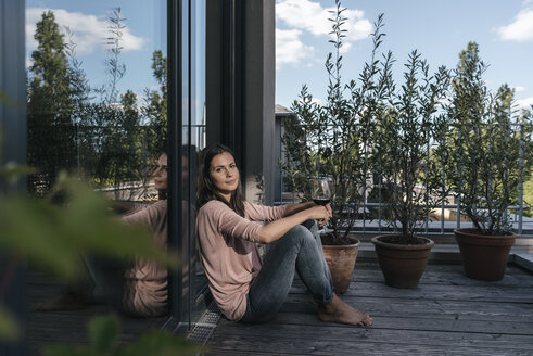 Frau mit Glas Rotwein entspannt auf Balkon - JOSF01690