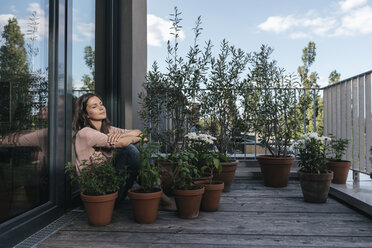 Woman relaxing on balcony surrounded by plants - JOSF01693