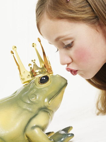Porträt eines kleinen Mädchens, das den Froschkönig küsst, lizenzfreies Stockfoto