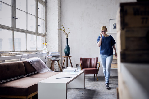 Lächelnde Frau am Telefon, die in ein Loft geht, lizenzfreies Stockfoto