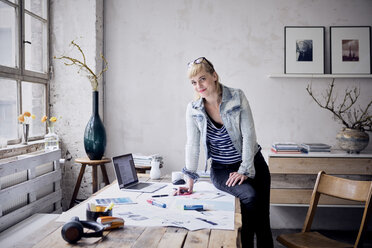 Lächelnde Frau am Schreibtisch in einem Loft - RBF05970