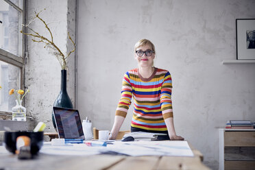 Porträt einer lächelnden Frau am Schreibtisch in einem Loft - RBF05977