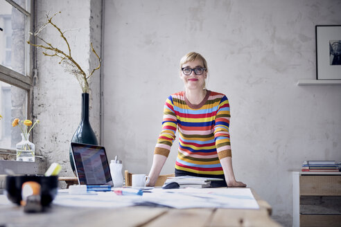 Portrait of smiling woman at desk in a loft - RBF05977