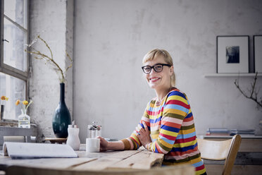 Portrait of laughing woman with cup of coffee in a loft - RBF05981