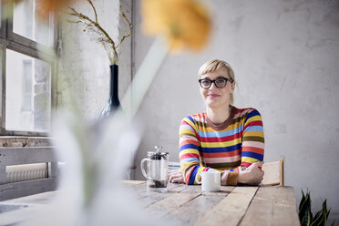 Porträt einer lächelnden Frau mit einer Tasse Kaffee in einem Loft - RBF05982