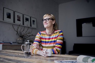 Porträt einer lächelnden Frau mit einer Tasse Kaffee in einem Loft - RBF05983