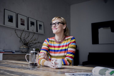 Portrait of smiling woman with cup of coffee in a loft - RBF05983