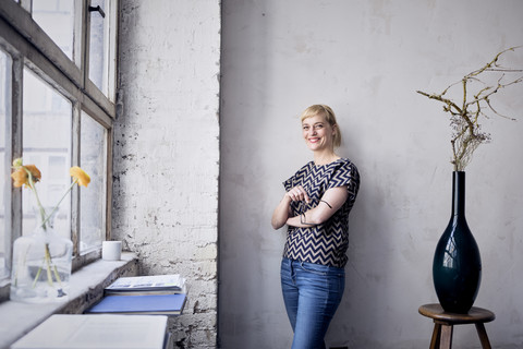 Portrait of laughing woman leaning against wall in loft stock photo