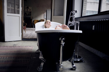 Woman taking bubble bath in a loft - RBF06017