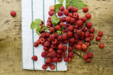 Himbeeren, Küchentuch und Blätter auf Holz - ASF06114