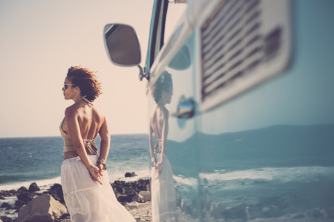 Spanien, Teneriffa, lächelnde Frau steht am Meer und schaut in die Ferne, lizenzfreies Stockfoto