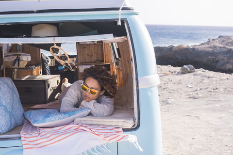 Spanien, Teneriffa, Frau entspannt sich in einem am Meer geparkten Lieferwagen, lizenzfreies Stockfoto