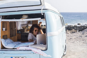 Spanien, Teneriffa, lächelnde Frau mit Blick auf Laptop in Lieferwagen - SIPF01710