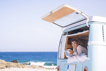 Spain, Tenerife, portrait of happy woman with coffee cup in van - SIPF01713