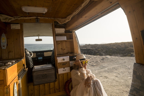 Spanien, Teneriffa, Frau sitzt in einem am Meer geparkten Lieferwagen, lizenzfreies Stockfoto