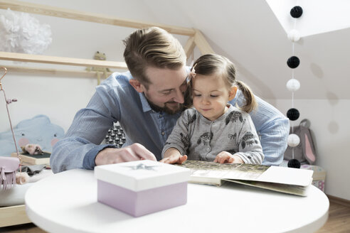 Vater und Tochter betrachten ein Fotoalbum in ihrem Kinderzimmer - SBOF00591