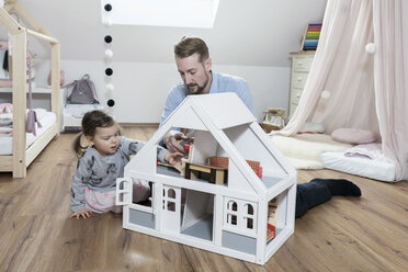 Vater und kleine Tochter spielen mit Puppenhaus in ihrem Kinderzimmer - SBOF00594