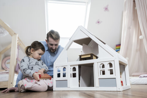 Vater und kleine Tochter spielen mit Puppenhaus in ihrem Kinderzimmer - SBOF00595
