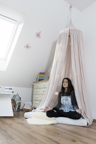 Mädchen meditiert im Kinderzimmer, lizenzfreies Stockfoto