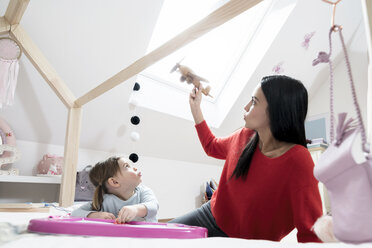 Mutter und kleine Tochter spielen mit Spielzeugflugzeug im Kinderzimmer - SBOF00605