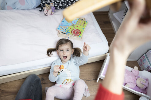 Kleines Mädchen, das auf die Hand seiner Mutter zeigt, die ein Spielzeugflugzeug hält - SBOF00606