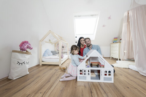 Glückliche Eltern im Kinderzimmer, während die kleine Tochter mit einem Puppenhaus spielt - SBOF00607