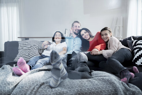 Glückliche Eltern und Zwillingstöchter auf dem Sofa im Wohnzimmer beim Fernsehen - SBOF00616