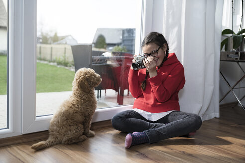 Mädchen, das ein Bild von ihrem Hund im Wohnzimmer macht - SBOF00620