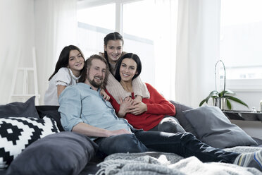 Family portrait of parents and twin daughters on sofa in living room - SBOF00625