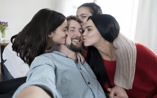 Vater macht ein Selfie, während Mutter und Zwillingstöchter ihn küssen - SBOF00627