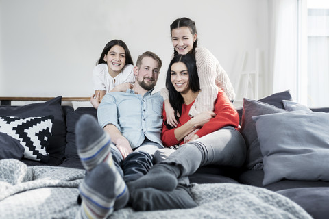 Family portrait of parents and twin daughters on sofa in living room stock photo