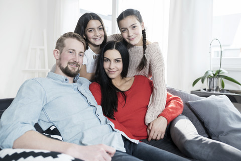 Family portrait of parents and twin daughters on sofa in living room stock photo