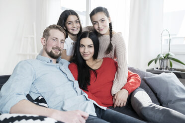 Family portrait of parents and twin daughters on sofa in living room - SBOF00630