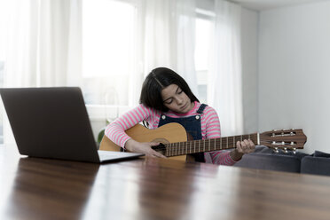 Girl playing guitar in front of laptop - SBOF00640