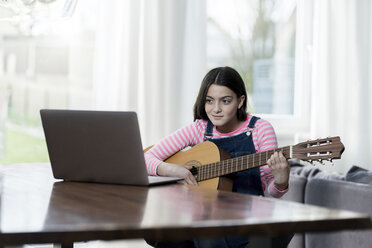 Girl playing guitar in front of laptop - SBOF00641