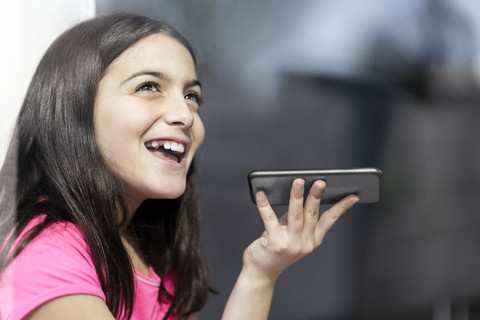 Mädchen in rosa Hemd spricht mit jemandem über ihr Smartphone, lizenzfreies Stockfoto