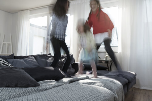 Mädchen springen auf dem Sofa im Wohnzimmer - SBOF00659