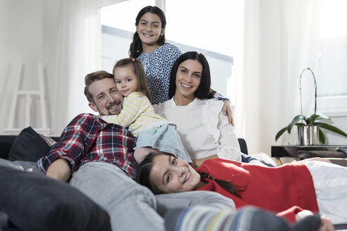 Porträt von Eltern und drei Töchtern auf dem Sofa im Wohnzimmer - SBOF00664