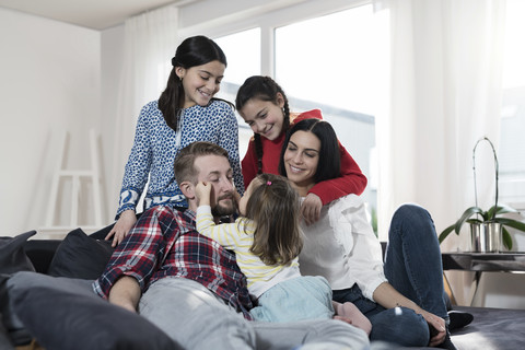 Parents and three daughers on sofa in living room stock photo