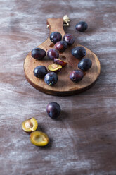 Sliced and whole plums on wooden board - MYF01953