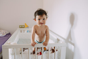 Portrait of happy baby girl in crib - GEMF01785